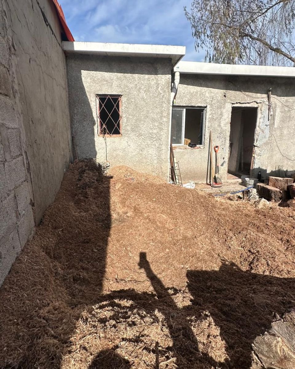 Después: el mismo patio sin el tocón, con la tierra removida junto al muro